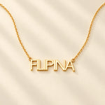 FLEURENZ FILIPINA uppercase 14k gold-filled nameplate necklace on an ivory background