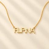 FLEURENZ FILIPINA uppercase 14k gold-filled nameplate necklace on an ivory background