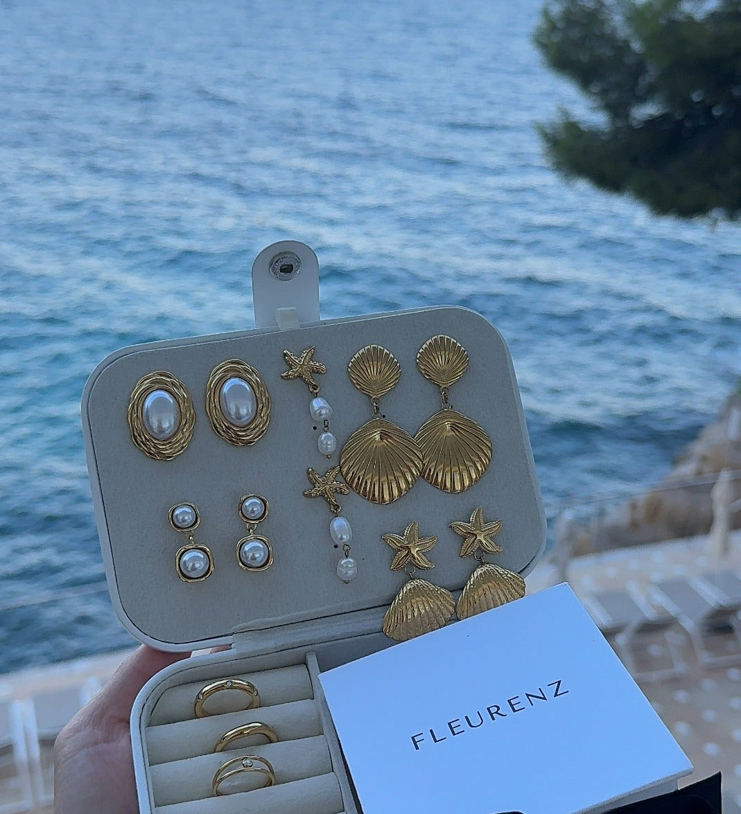 FLEURENZ shell and pearl jewelry in a travel case overlooking the ocean