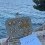 FLEURENZ shell and pearl jewelry in a travel case overlooking the ocean
