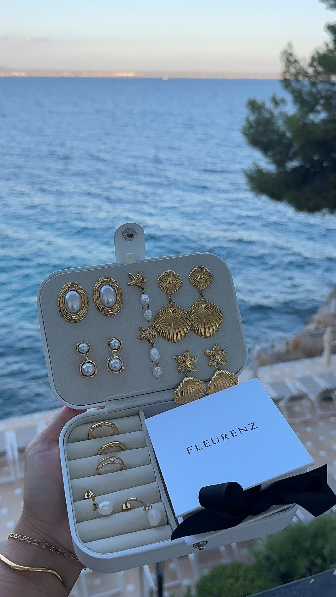 FLEURENZ shell and pearl jewelry in a travel case overlooking the ocean